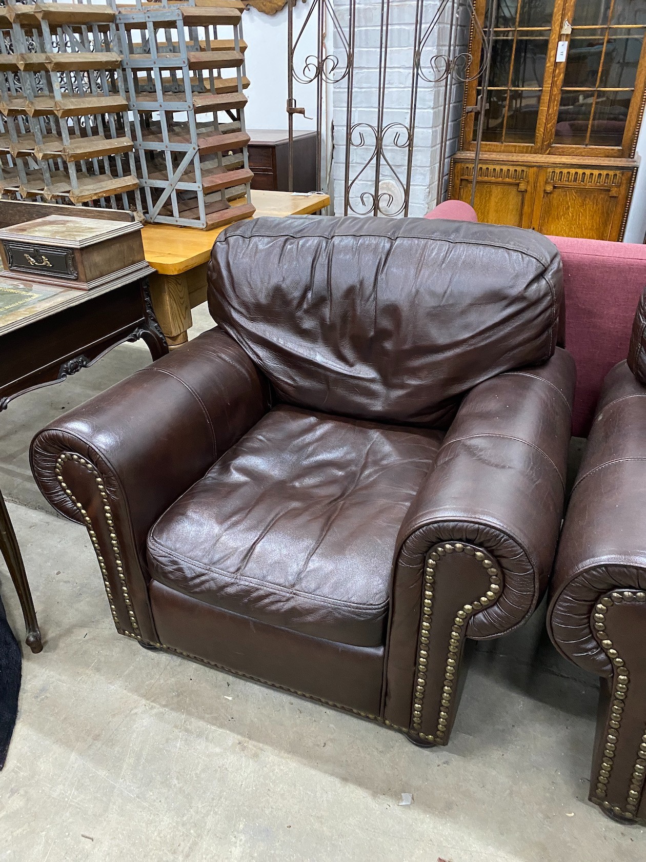 A pair of contemporary studded brown leather armchairs, width 98cm, depth 84cm, height 80cm
